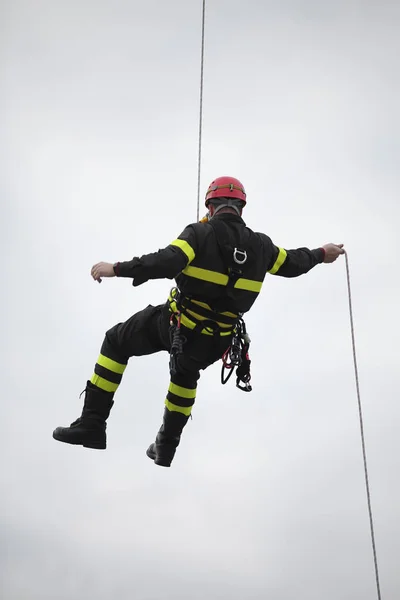 Harassed fireman hanging from a cord suspended in vacuum — Stock Photo, Image