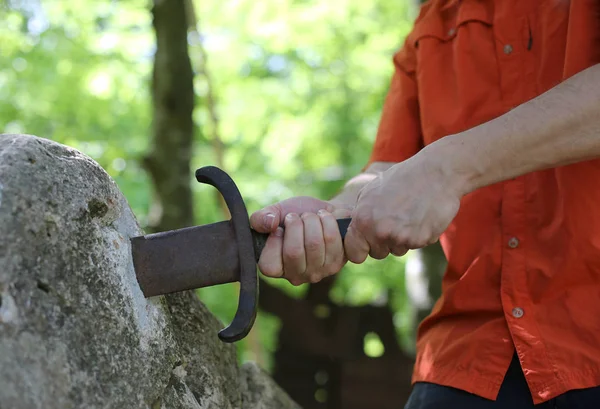 Mãos e a lendária espada Excalibur na pedra — Fotografia de Stock