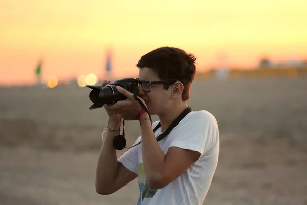 Хлопчик фотографує захід сонця на морі — стокове фото