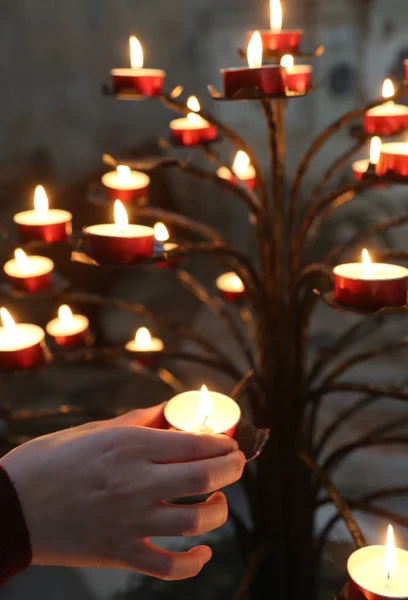 Mão de criança e muitas velas na igreja durante o santo mas — Fotografia de Stock