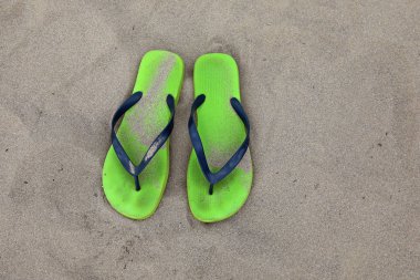 Kumsalda iki yeşil parmak arası terlik.