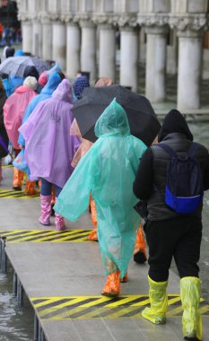 Renkli yürüyüşçüler, su geçirmez giysiler ve turistler