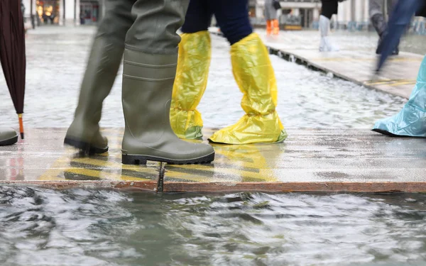 Emberek gumicsizmával és műanyag lábszárvédővel Velencében Olaszország — Stock Fotó