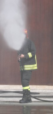İtfaiyeci büyük bir yangını söndürmek için nebulize köpük kullanıyor.