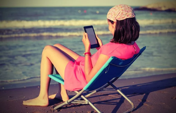 Petite fille lit l'ebook sur la plage — Photo