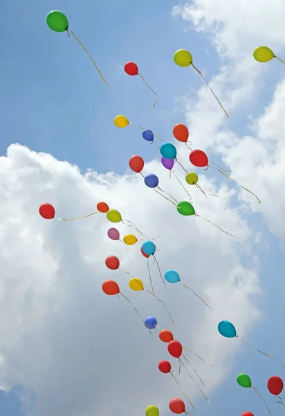 Dúzia de balões coloridos no céu com muitas nuvens brancas simbolizam — Fotografia de Stock