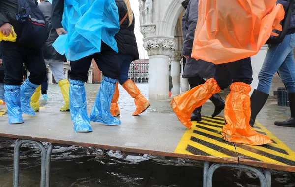 People with plastic leggings on the footbridge in Venice in Ital — Stock Photo, Image