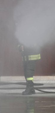 İtfaiyeci yangını söndürmek için yangın musluğu kullanıyor.