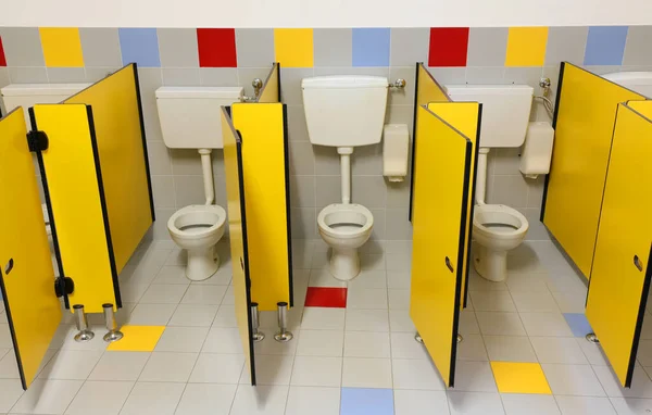 Tre toaletter i ett badrum plantskola med gula dörrar — Stockfoto