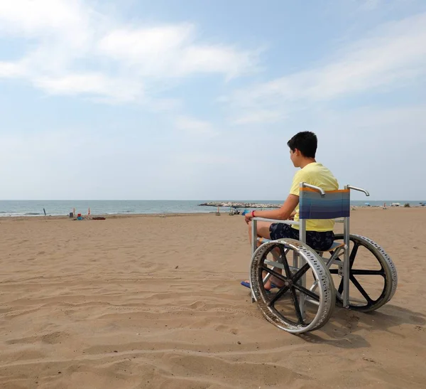 특수 휠체어를 탄 소년 이 바다를 바라봅니다 — 스톡 사진