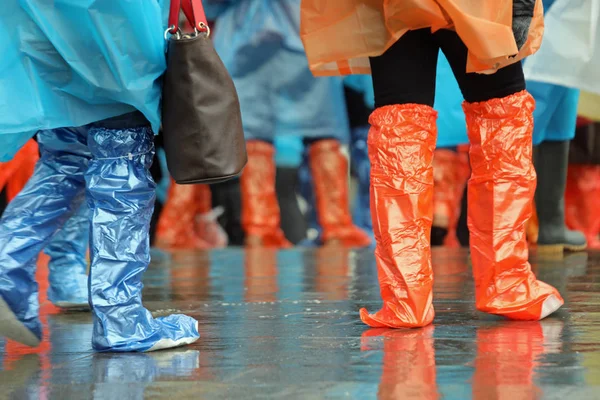 Menschen mit Gamaschen und regenfesten Regenmänteln während des Regens — Stockfoto
