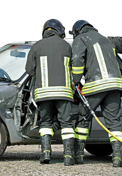 Odważni strażacy, którzy otwierają zniszczone drzwi samochodu za pomocą — Zdjęcie stockowe