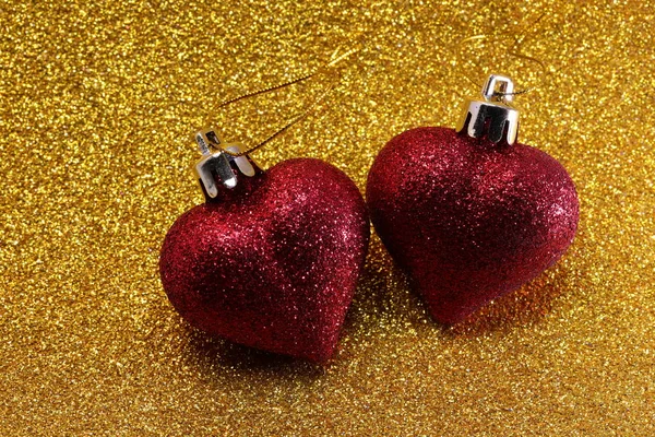 Dos corazones de purpurina roja sobre fondo dorado brillo — Foto de Stock