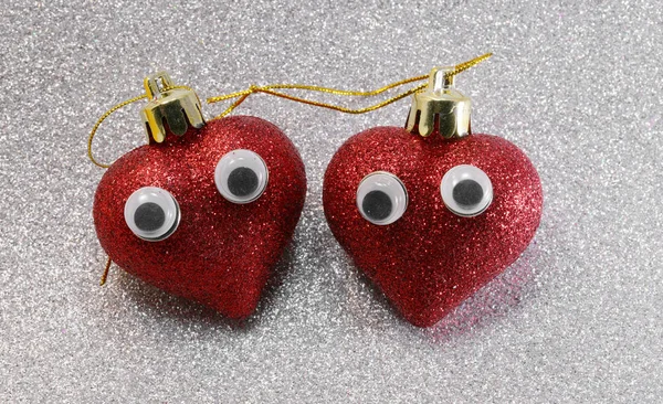 Twee ogen op rode glitter hartjes op glinsterende zilveren achtergrond — Stockfoto