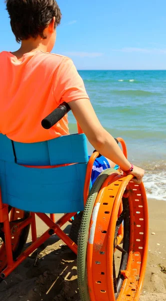 Jeune perosn sur un fauteuil roulant regarde la mer — Photo