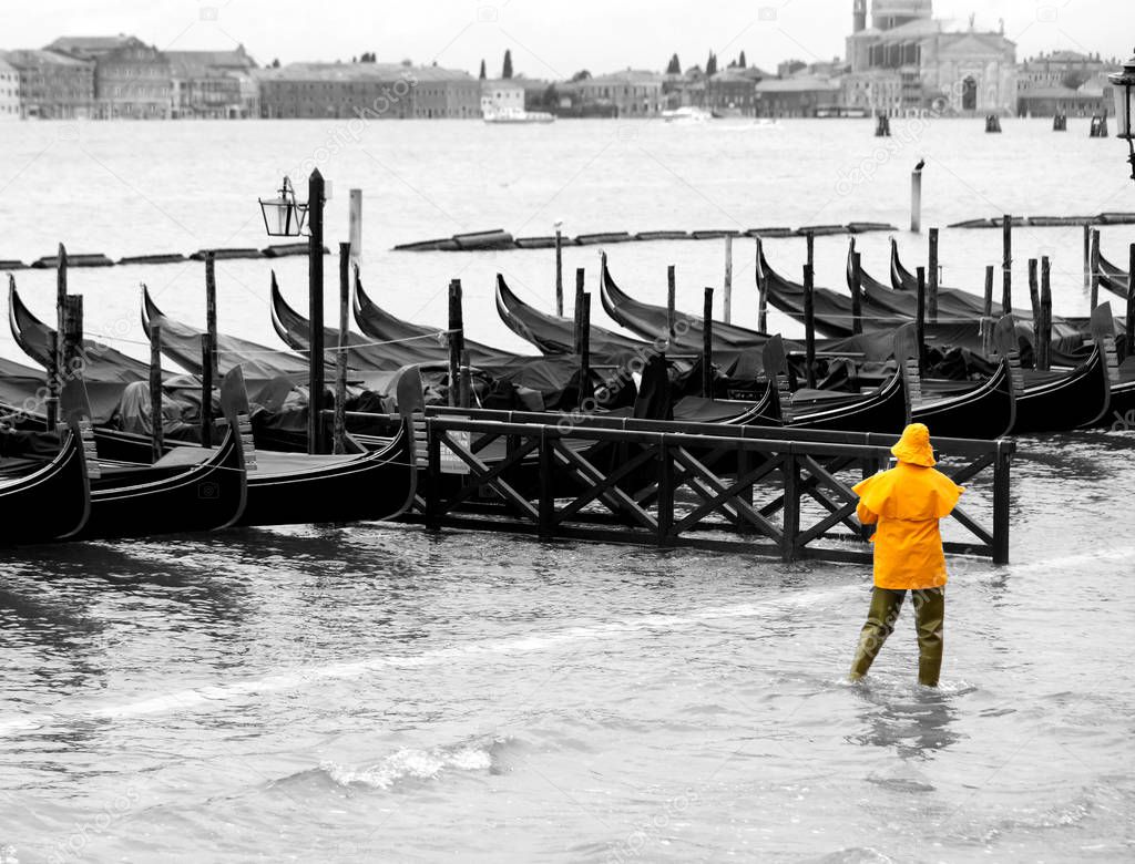 gondolas boats and a man in yellow in Venice Italy with black an