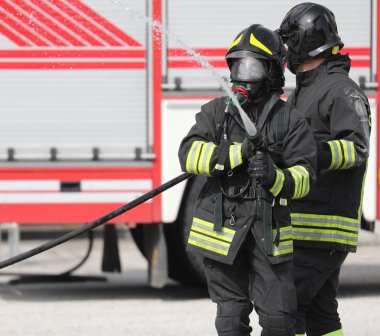 firemen with hose hydrant in action and fire engine