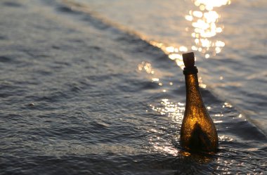 bottle with the secret message in the sea at sunse