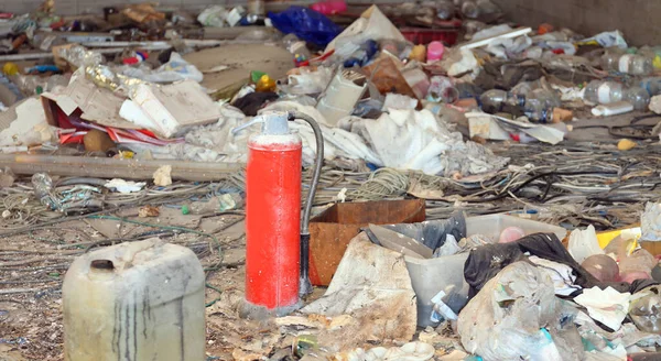 Refugio para indigentes con basura y un extintor rojo roto — Foto de Stock