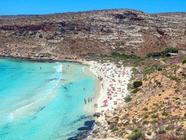 Mavi denizli körfez ve kumsalda yüzenler.