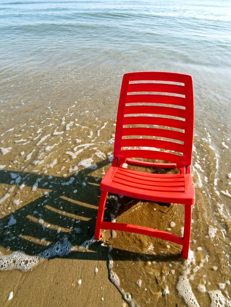 Червоний стілець посеред моря — стокове фото