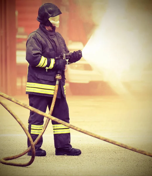 Firefighter during fire extinguishing and old toned effect — Stock Photo, Image