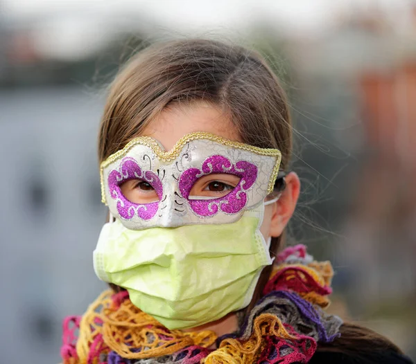 健康マスクとウイルスクラウンから保護するためのカーニバルマスクを持つ若い女の子 — ストック写真