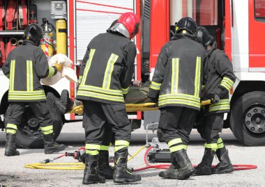 Trafik kazasından sonra yaralı ve sedyeli itfaiyeciler.
