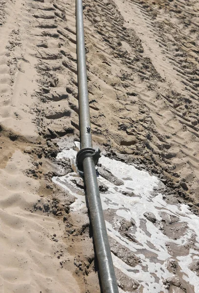 water pipe with a leak that causes the liquid to leak into the dry arid soil in summer