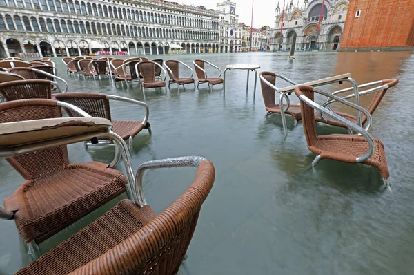chairs and tables of a bar submerged by the high tide in Piazza San Marco in Venice