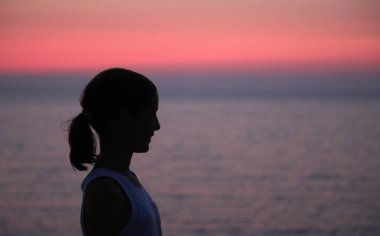Güneş denizin üzerinde batarken bir kızın profiline bürünmüş yüz.