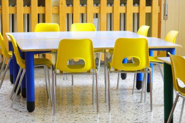 Çocukların olmadığı bir okulun sınıfında sarı küçük sandalyeler.