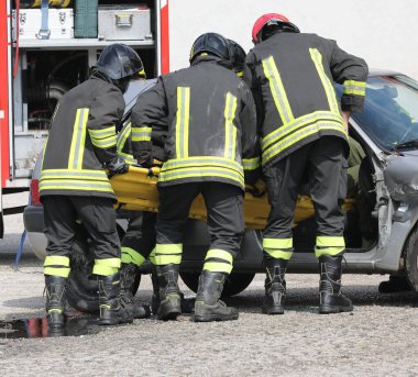 Üniformalı itfaiyeciler kazadan sonra sedyeyle yaralıları arabadan çıkardılar.