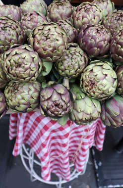 Large green artichokes outside the restaurant in Rome on top of a red and white checkered table clipart