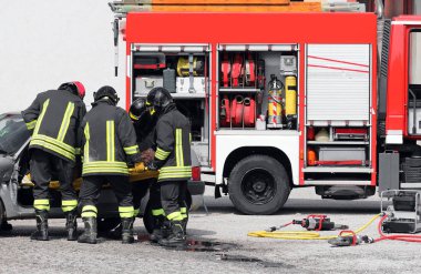 fire truck and firefighters with the stretcher extract the injured from the car after the road accident