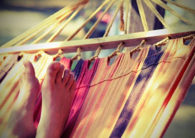 barefoot feet of the little girl while resting on the hammock in the summer with an antiqued effect