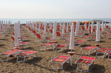 sunny with closed umbrellas and red deck chairs and the blue sky in the early morning