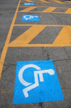 Asfalttaki mavi ve beyaz tabelalar engelliler için park yeri olduğunu gösteriyor