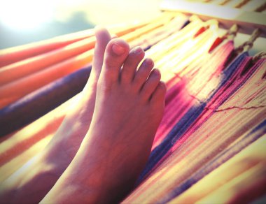 Turist köyünde yazın hamakta dinlenirken küçük kızın yalınayak ayaklarıyla ve antika bir efektle