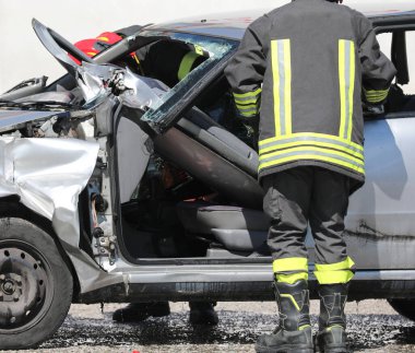 Bay ve kasklı itfaiyeci ve trafik kazasından sonra bozuk bir araba.