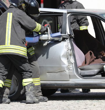 İtfaiyecilerden oluşan ekip, kazadan sonra büyük bir kesikle hasar arabasını açıyor.