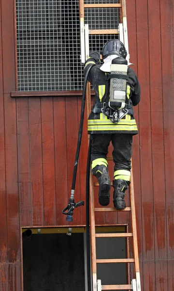 消防队员用氧气筒爬上梯子 即使在有害的空气中也能呼吸 — 图库照片
