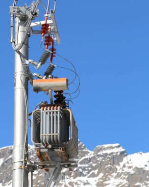 Elektrik trafosu ve yüksek voltajlı elektrik kabloları olan bir direk.