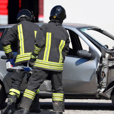 Bay ve kasklı itfaiyeciler trafik kazasından sonra bozuk bir arabayı açtılar.