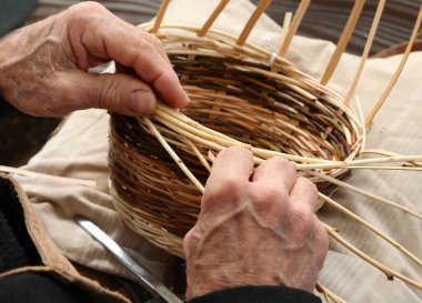 Yaşlı beyefendi elleriyle hasır bir sepet yapıyor.