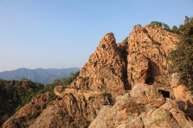 Korsika 'da D81 denen yol manzarası ve gün batımında kırmızı kayalar.