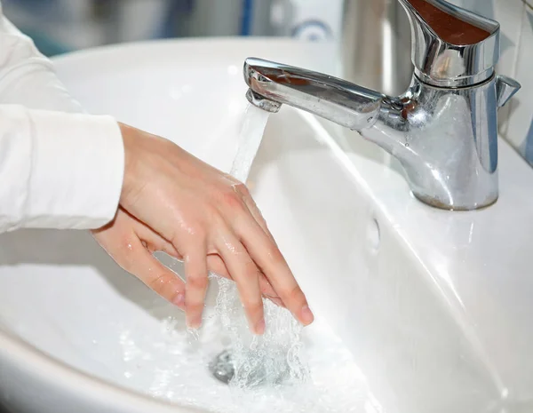 用水龙头里流出的水洗了洗碗槽里女孩的手 — 图库照片