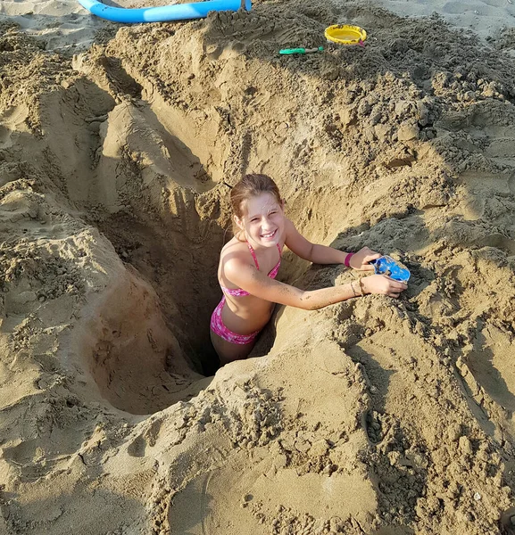 Leende Liten Flicka Leker Inne Ett Djupt Hål Sanden Stranden — Stockfoto