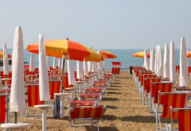 İnsanlar olmadan bir turist köyünün özel plajında sıra sıra sandalye ve şemsiyeler.