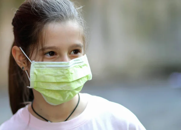 コロナウイルスによって引き起こされるロックダウン中に緑色の外科マスクを持つかなり小さな女の子 — ストック写真